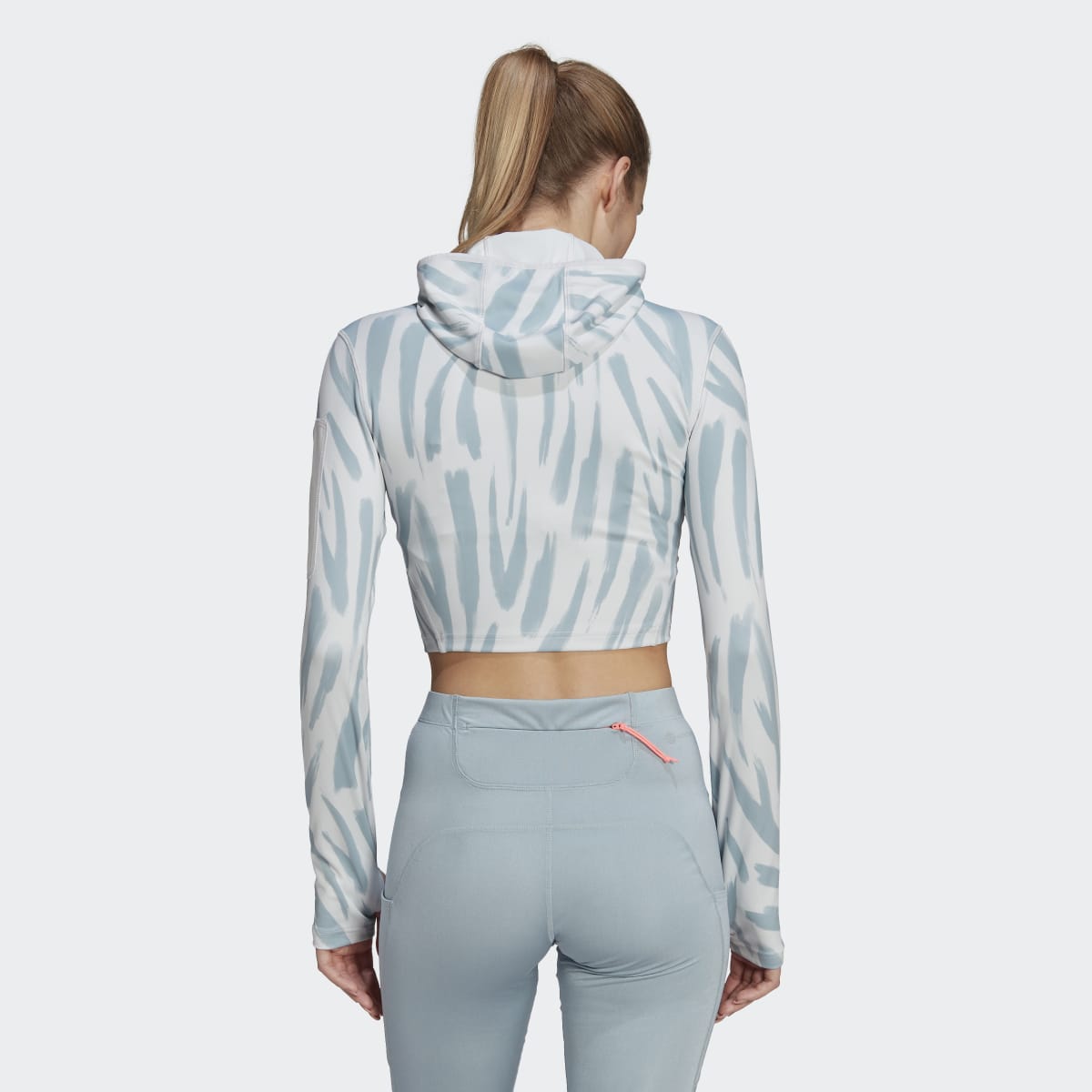 Adidas hooded crop top with zebra print and light blue leggings. Rear view.